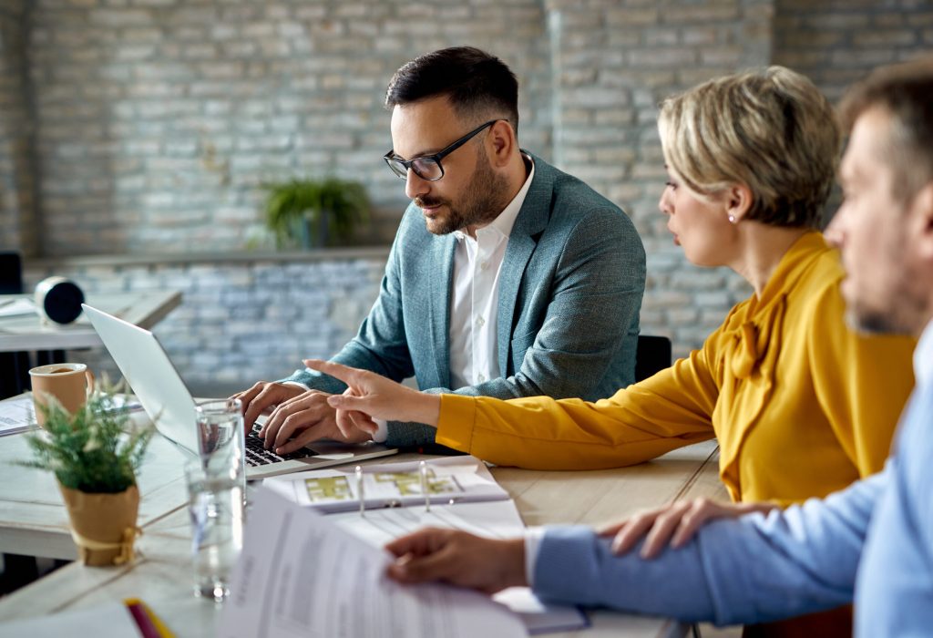 Financial advisor working on a computer while having a meeting with a couple in the office.